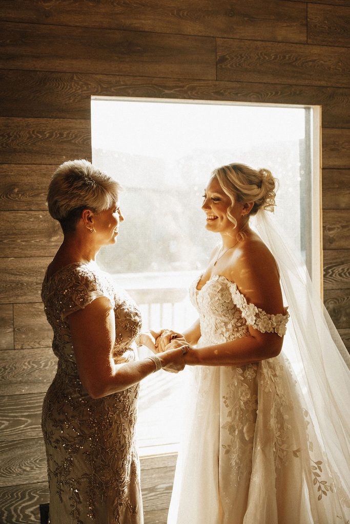 A mother of the bride holding hands with her daughter.