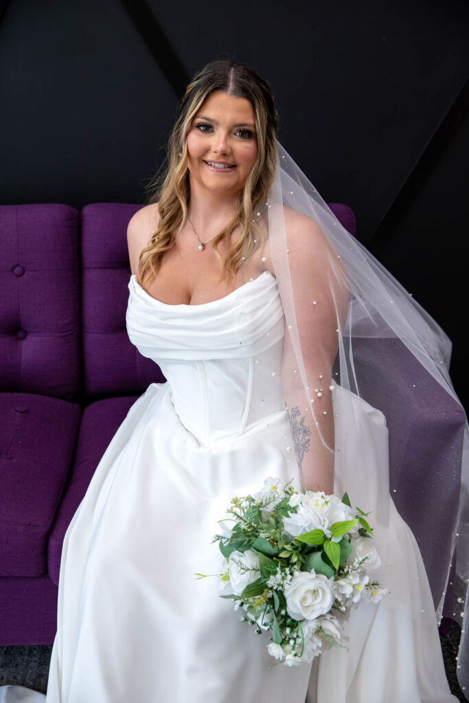 Bride with a veil sitting on the purple couch at Catherine's Bridal Boutique in Valparaiso Indiana